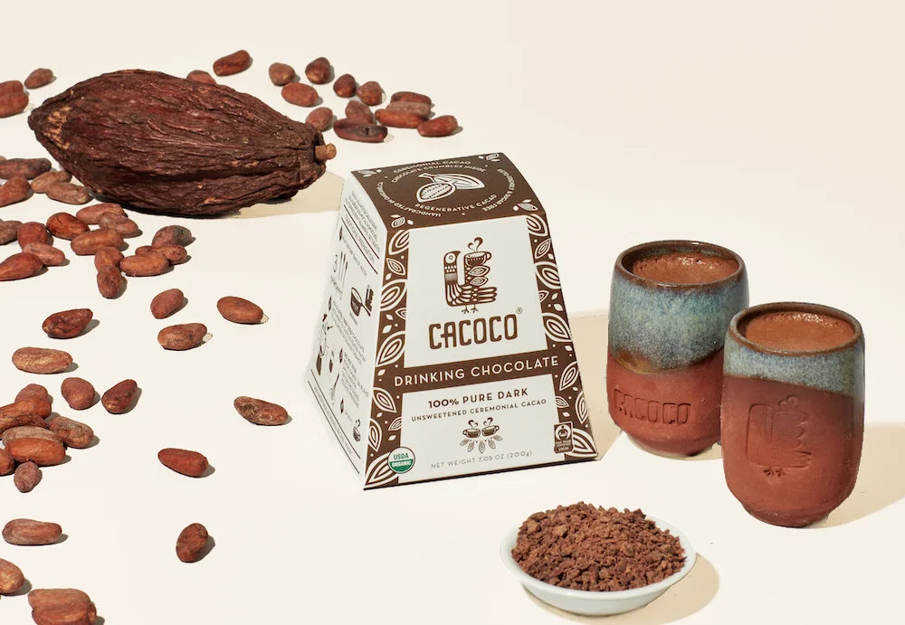 A warm, rich cup of ceremonial cacao with organic ingredients, ready to provide mood-boosting, heart-opening benefits, surrounded by raw cacao beans and a cinnamon stick for added flavor.