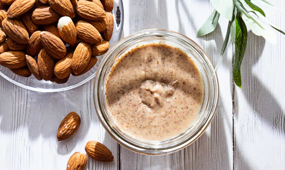 A jar of creamy organic almond butter alongside whole almonds, highlighting its rich texture and health benefits.